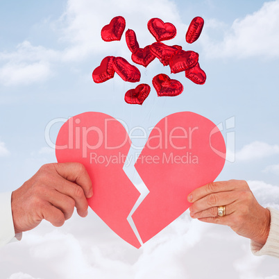 Composite image of couple holding a broken paper heart