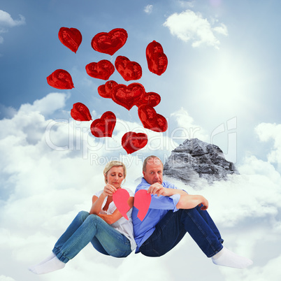 Composite image of sad mature couple holding a broken heart