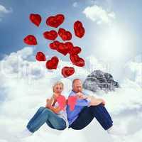 Composite image of sad mature couple holding a broken heart
