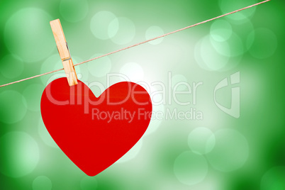 Composite image of heart hanging on line