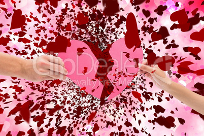 Composite image of hands holding two halves of broken heart