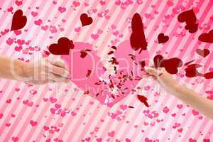 Composite image of hands holding two halves of broken heart