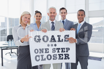 Composite image of business team holding large blank poster and