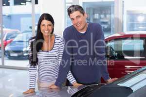 Smiling couple leaning on car