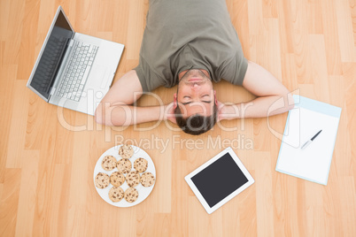 Man lying on floor surrounded by various objects at home