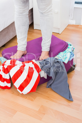 Woman standing on baggage to close it