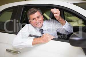 Smiling man holding a car key sitting in his car