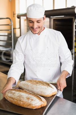 Happy baker holding tray of fresh bread