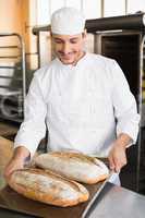 Happy baker holding tray of fresh bread