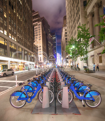 A row of blue bicycles on New York street at night