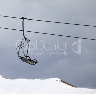 Chair lift and off-piste slope at gray windy day