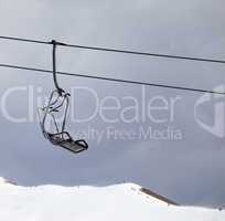 Chair lift and off-piste slope at gray windy day
