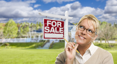 Young Woman in Front of For Sale Sign and House