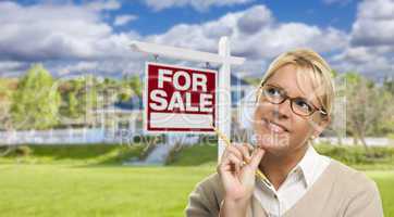 Young Woman in Front of For Sale Sign and House