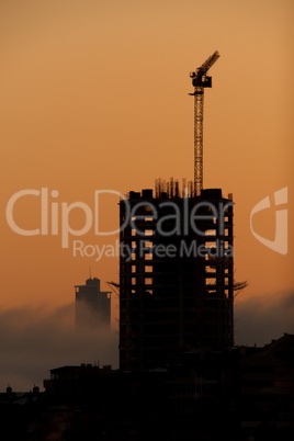 Dawn silhouette of office block with crane