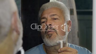 elderly man shaving and performing various grooming activities to the face