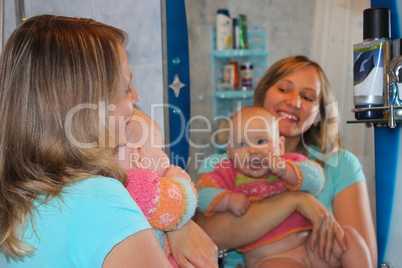 happy mother with her little daughter in front of mirror