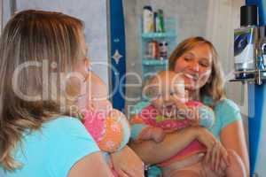 happy mother with her little daughter in front of mirror