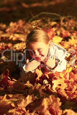 little girl laying in yellow leaves