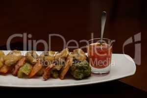 Tempura vegetable platter with glass of sauce