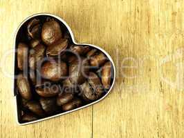 Heart and Coffee beans close-up on wooden, oak table.