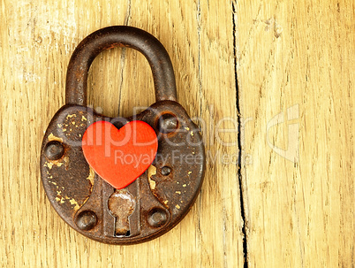 Rusty padlock and heart on a wooden background.