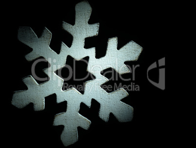 Huge white wooden snowflake and black background.