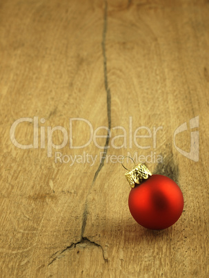 Red Christmas bauble on a wooden oak background.