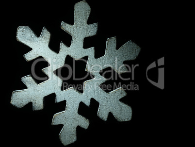 Huge white wooden snowflake and black background.