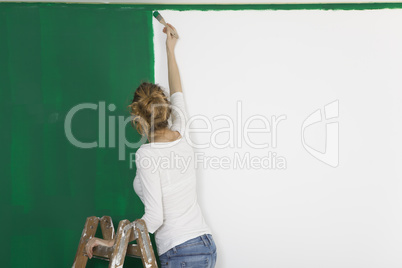 Frau mit Pinsel vor gruener Wand