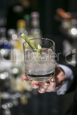 Hand hält ein Glas mit einem Long Drink (Moscow Mule) in einer Bar