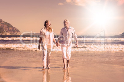 Happy couple walking barefoot on the beach