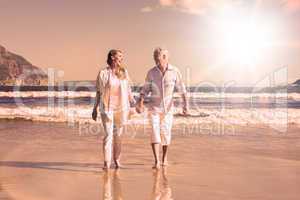 Happy couple walking barefoot on the beach