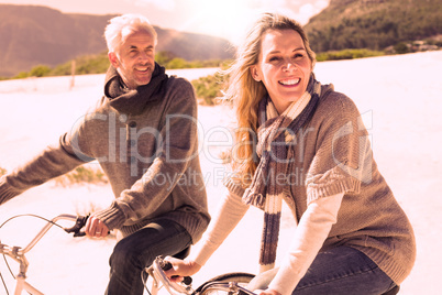 Carefree couple going on a bike ride on the beach