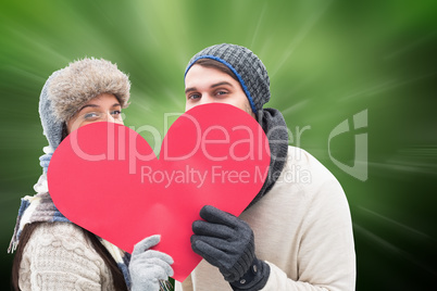 Composite image of attractive young couple in warm clothes holdi