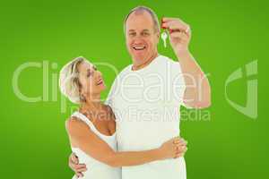 Composite image of mature couple smiling at camera with new hous