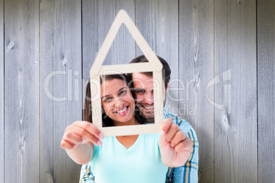 Composite image of happy young couple with house shape