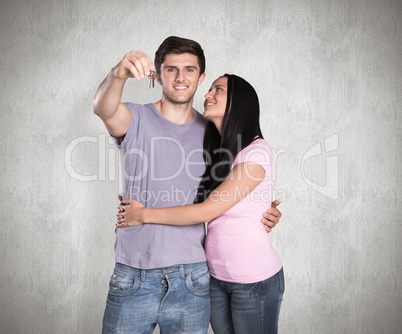 Composite image of young couple showing keys to house