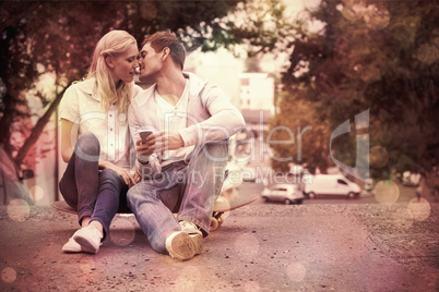 Cute young couple sitting on skateboard kissing