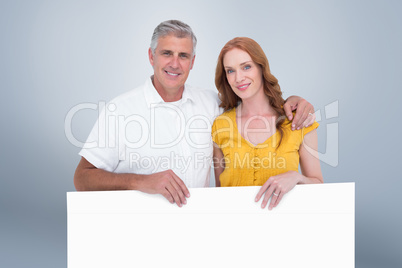 Composite image of casual couple showing a poster