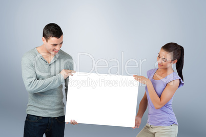 Composite image of young couple presenting banner together