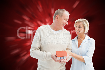 Composite image of happy mature couple with model house