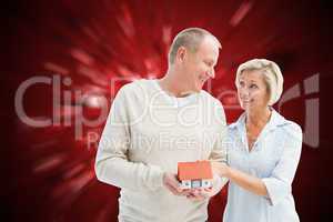 Composite image of happy mature couple with model house