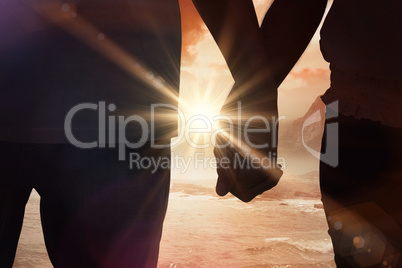 Composite image of young couple holding hands in the park