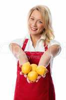 Frau mit Schürze präsentiert eine Handvoll Zitronen