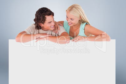 Composite image of cute happy couple leaning on a whiteboard