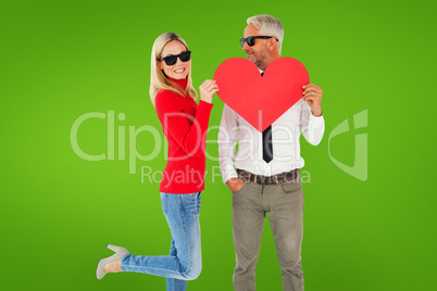 Composite image of cool couple holding a red heart together