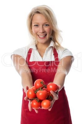 Frau mit Schürze zeigt eine Handvoll Tomaten