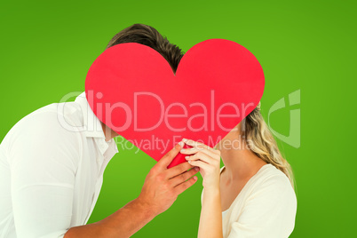 Composite image of attractive young couple kissing behind large