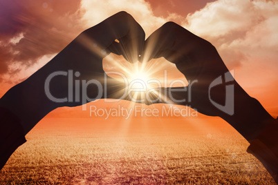 Composite image of woman making heart shape with hands